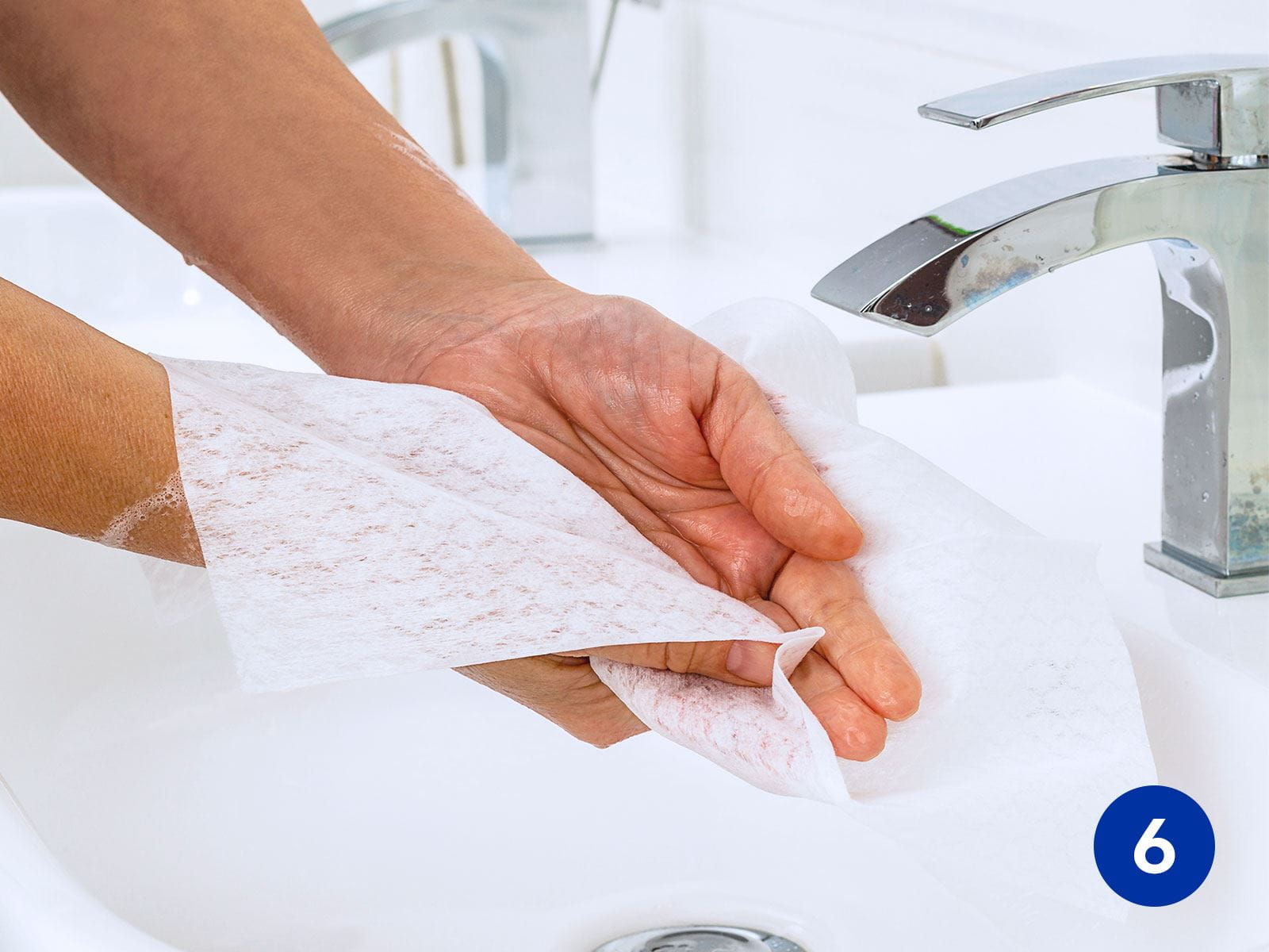 View of a person patting their hands dry with a soft white towelette.