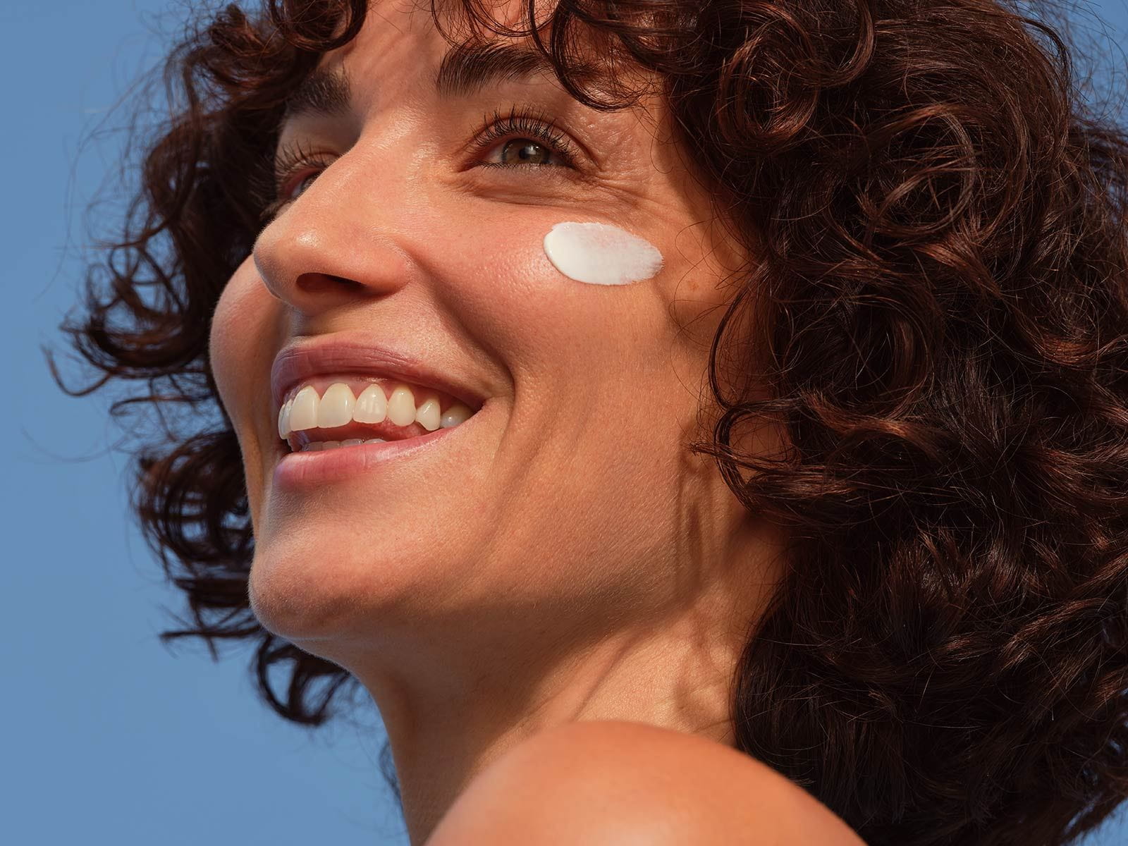 A person seen staring off into the distance with a NIVEA product smeared onto the left side of their face.