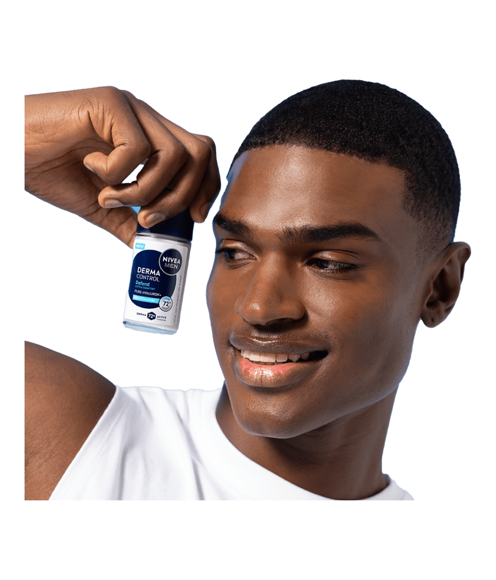A young smiling man looks to the side while holding up NIVEA MEN Derma Control Defend Deo Roll-On.