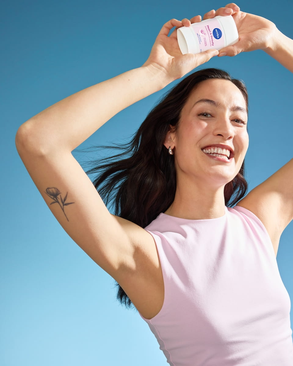 Jeune femme en robe rose utilisant le déodorant Nivea