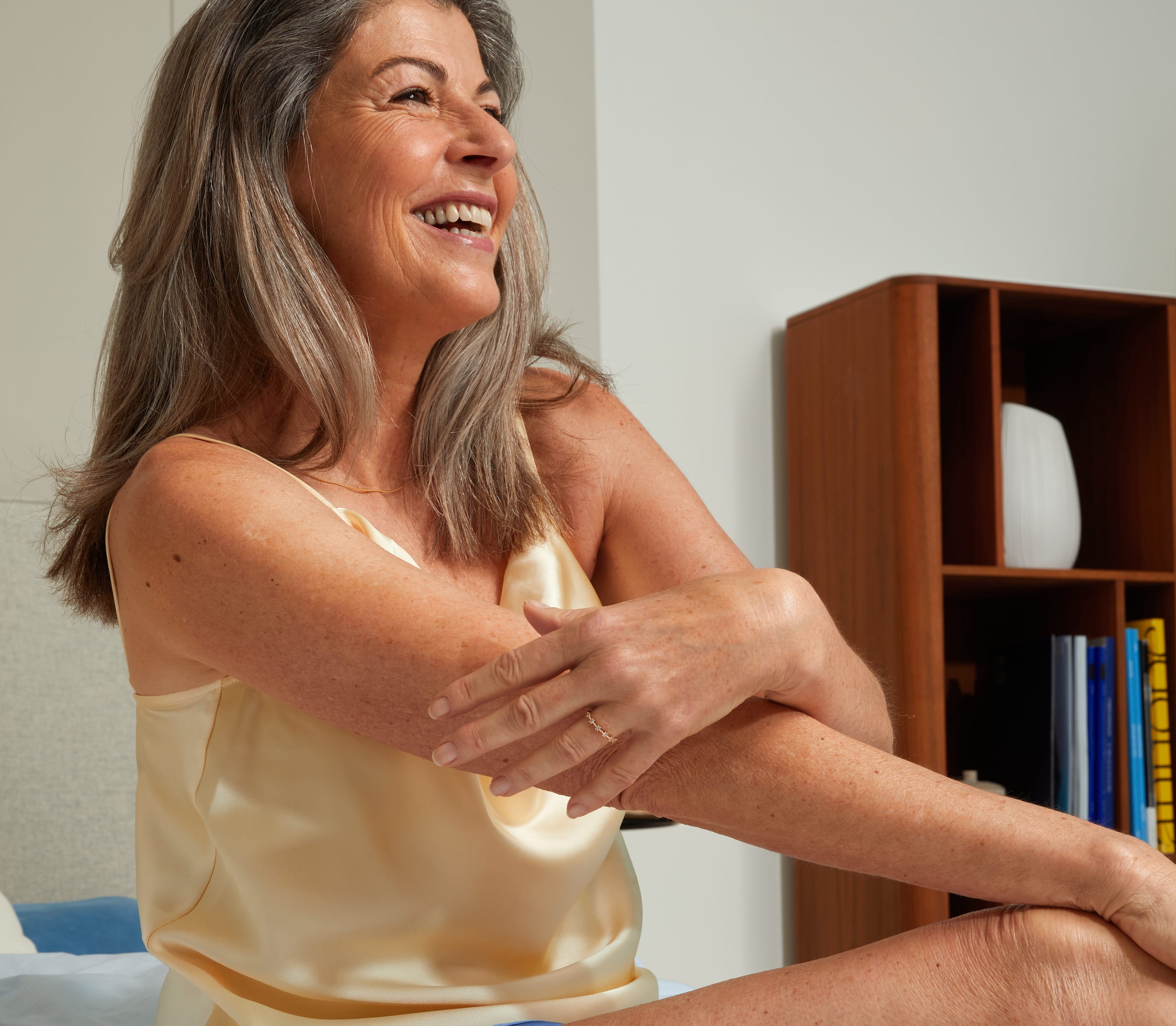 Kvinna sitter på sängen och smörjer in sig