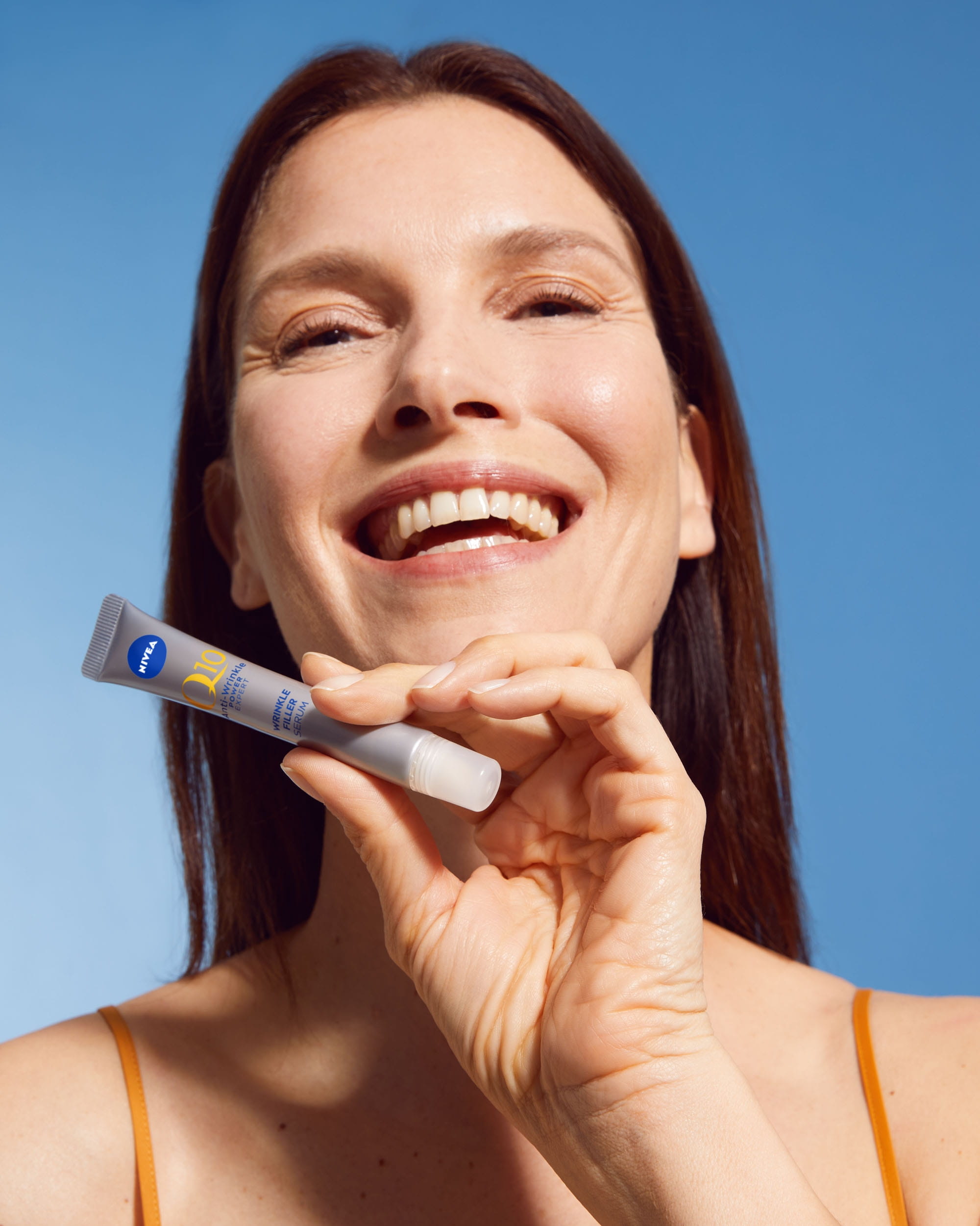 En person som ler och håller i en NIVEA produkt
