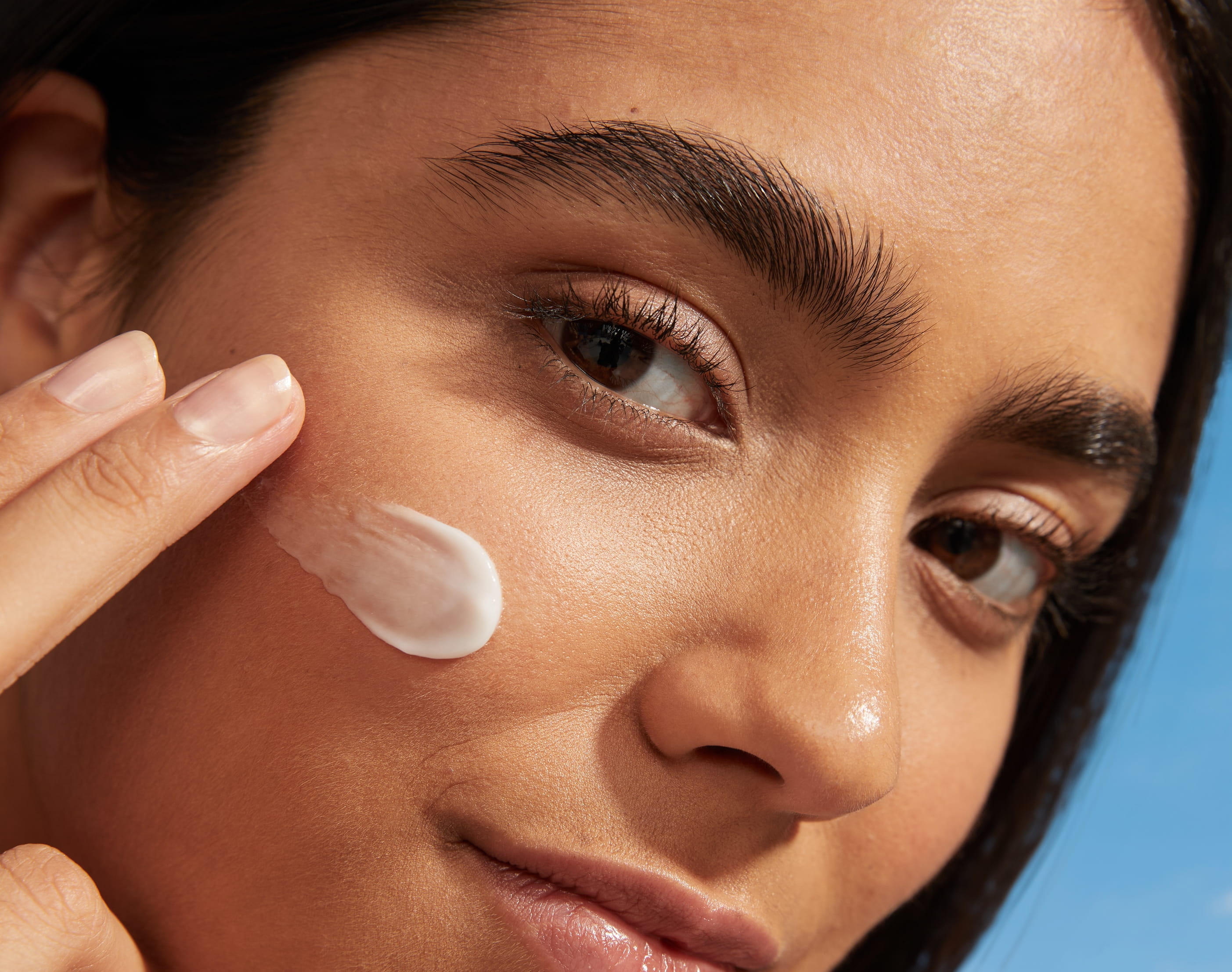 En närbild på en person som har kräm på kinden och tittar in i kameran