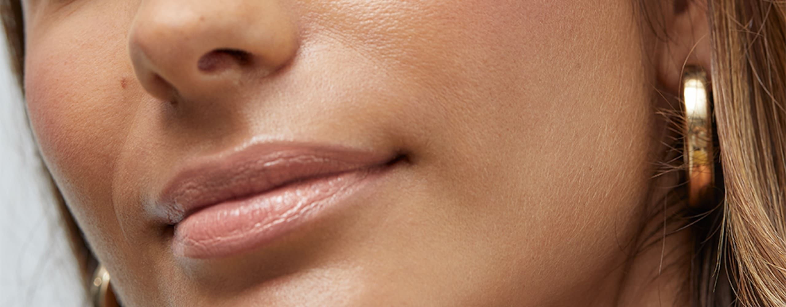 mujer pelirroja con una crema facial Nivea Q10 en la mano