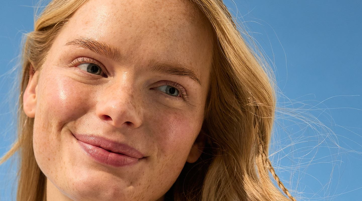 Femme blonde se nettoie la joue avec un cotton