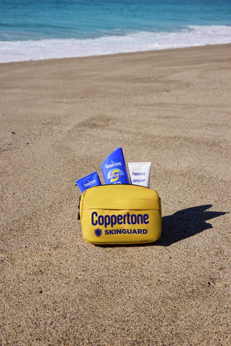 Coppertone Skinguard pouch and sunscreen bottles on a sandy beach