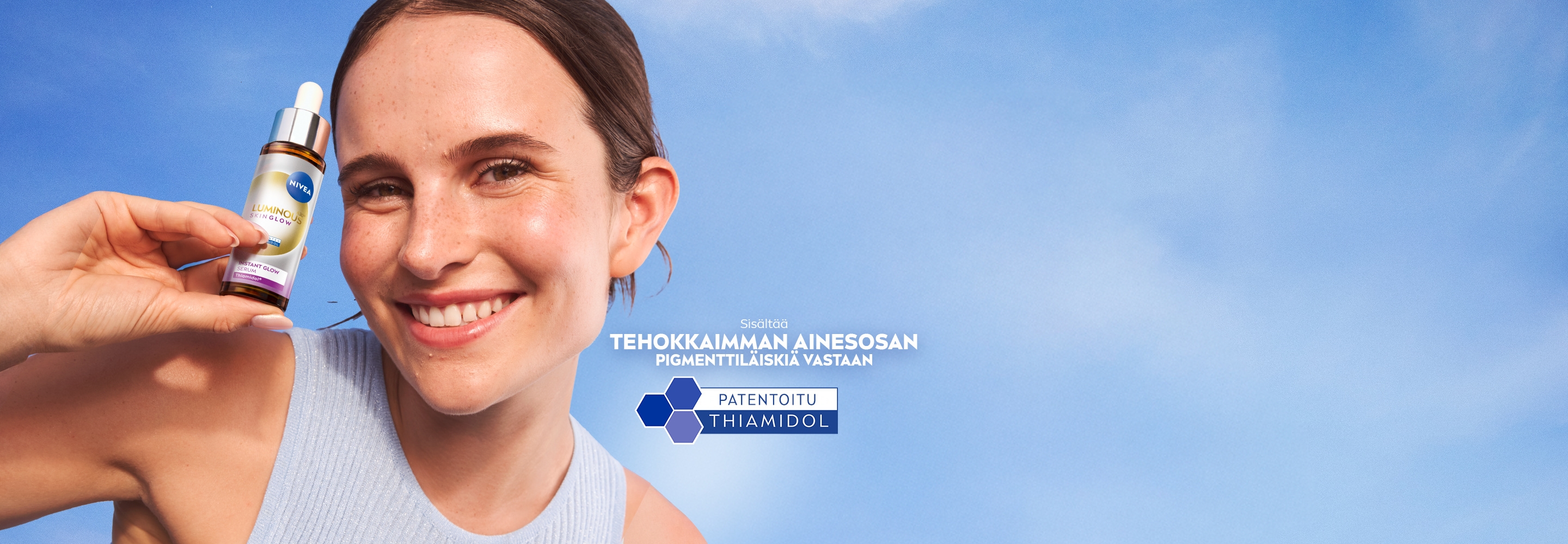 Nuori nainen hymyilee pidellessään NIVEA LUMINOUS630® Skin Glow -seerumia.