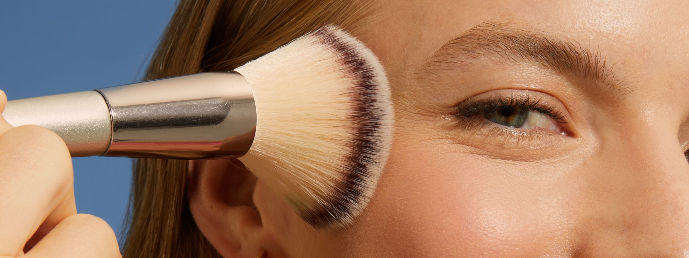 Woman using a make up brush on her face after using NIVEA SUN 2in1 Primer Daily UV Serum as a primer