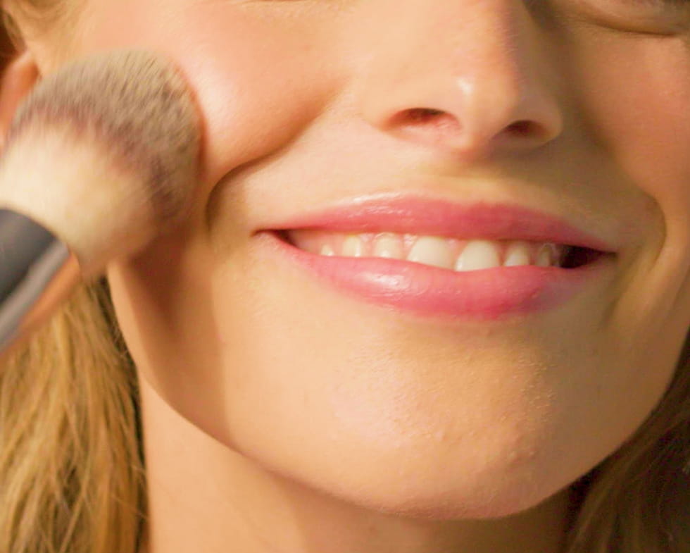 Woman applying thin layer of make up with brush