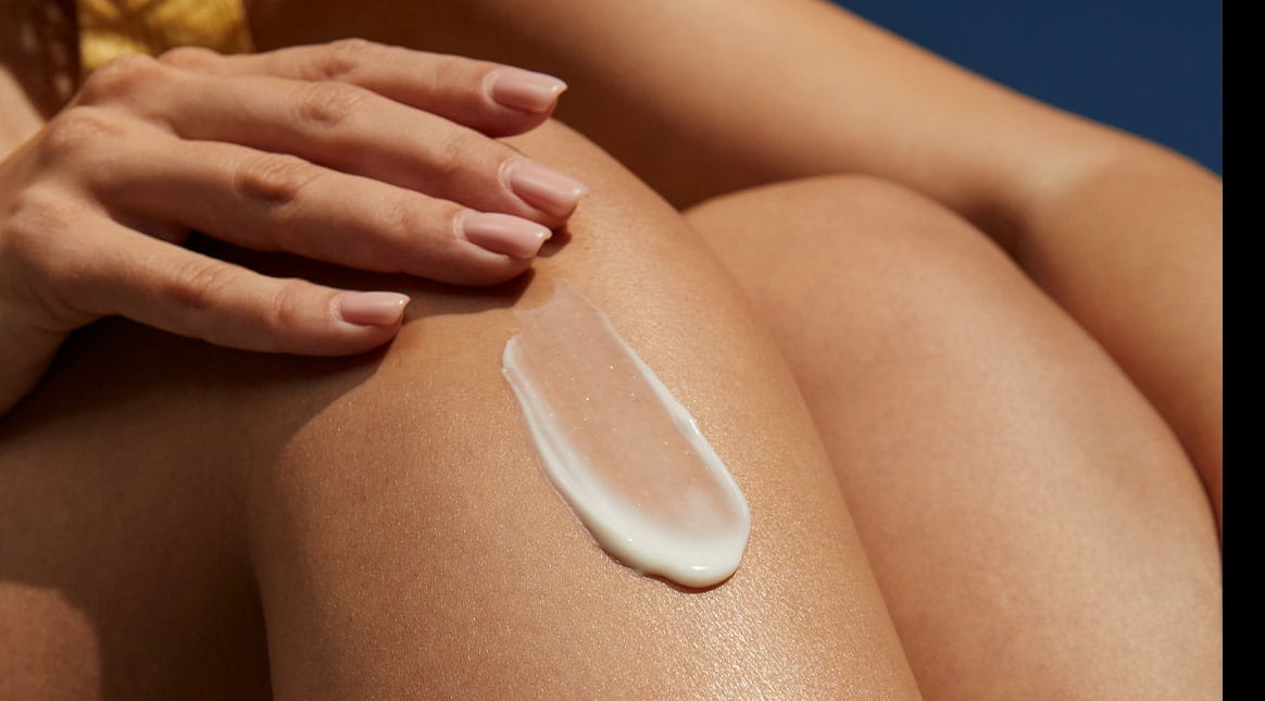 A view of a person smiling while looking straight into the camera lens, against a beige-coloured background.