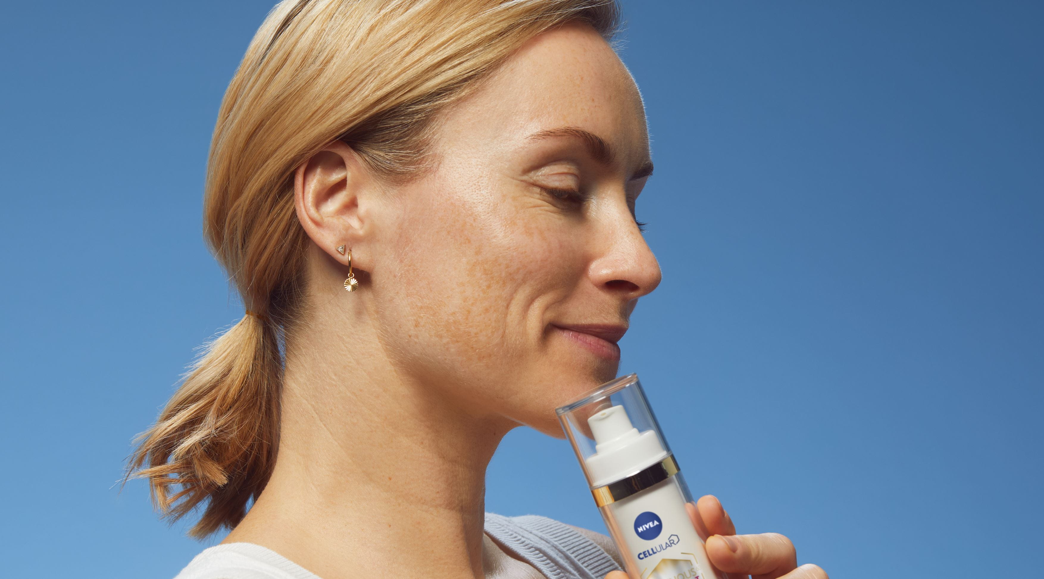 Kvinna i profil, hon håller NIVEA Luminous serum