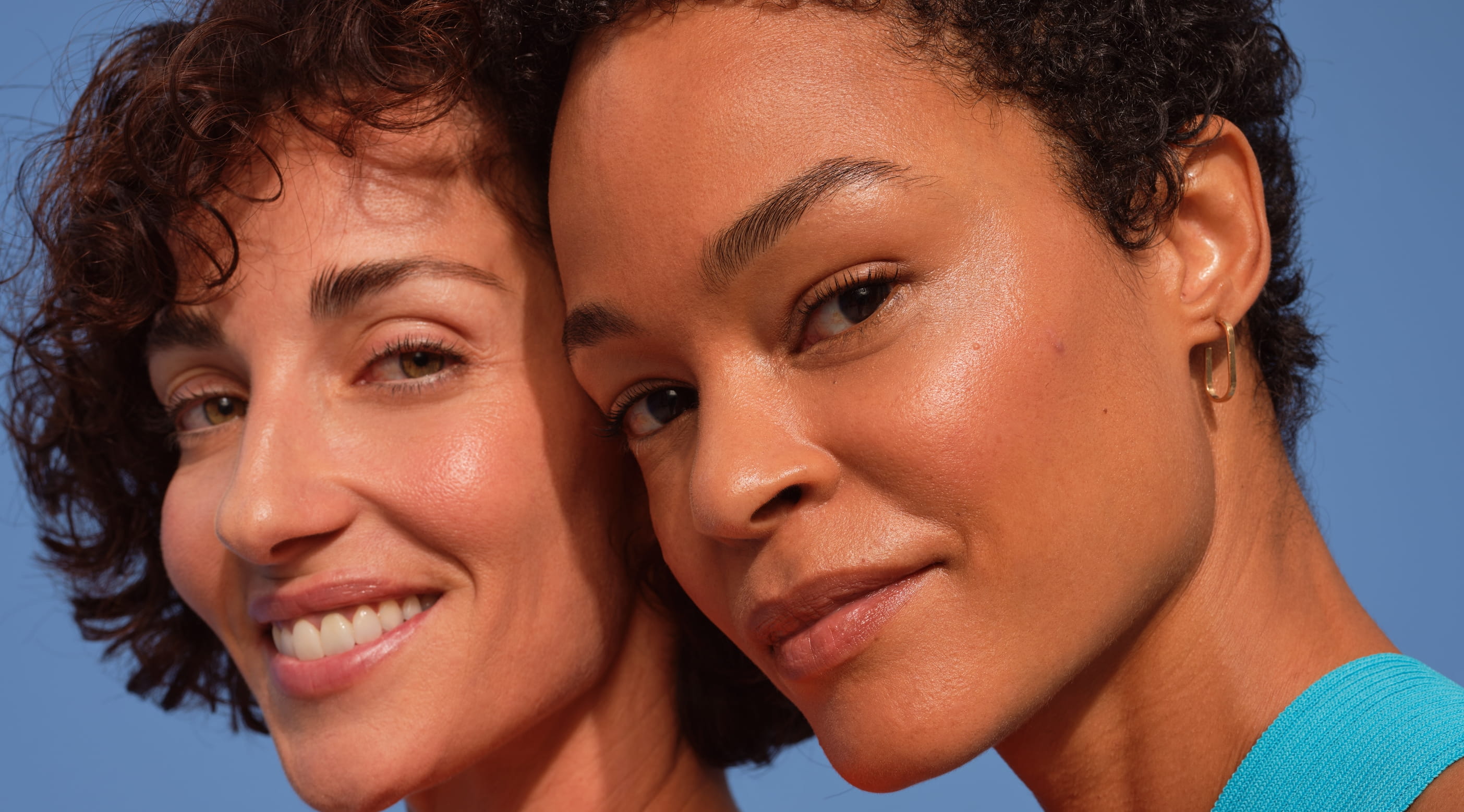 Två personer i profil, ler och tittar in i kameran