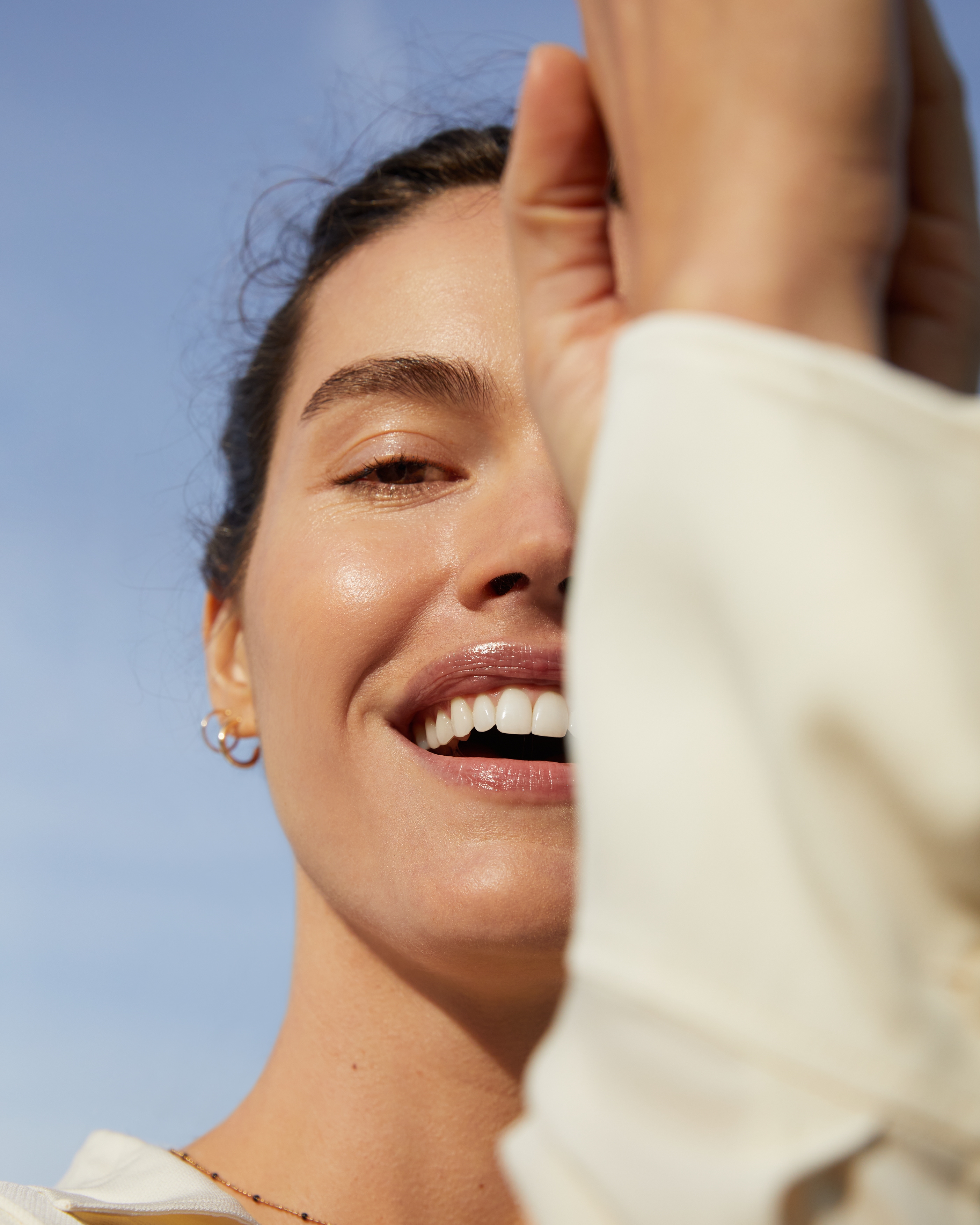 Tjej skrattar, håller upp armarna för halva ansiktet