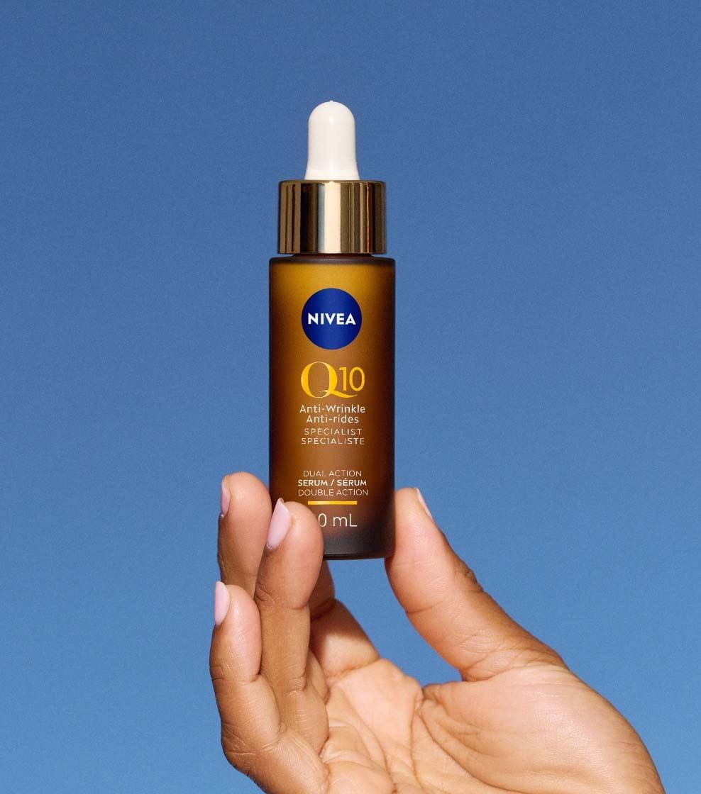 "A 30ml copper-brown bottle of NIVEA Q10 ANTI-WRINKLE SPECIALIST DUAL ACTION SERUM against a blue background. "