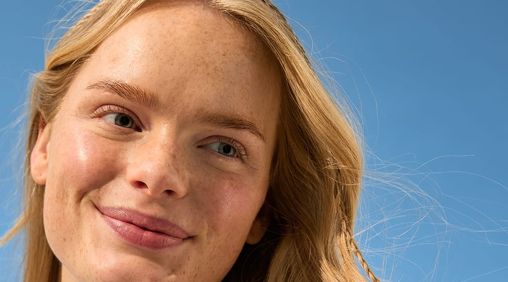 Jonge vrouw met blond haar staande in de zon