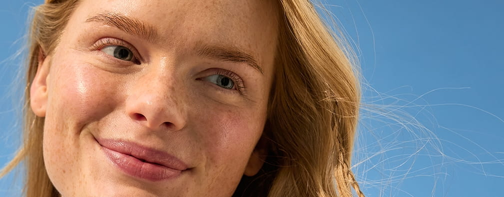 Giovane donna con capelli biondi in piedi al sole