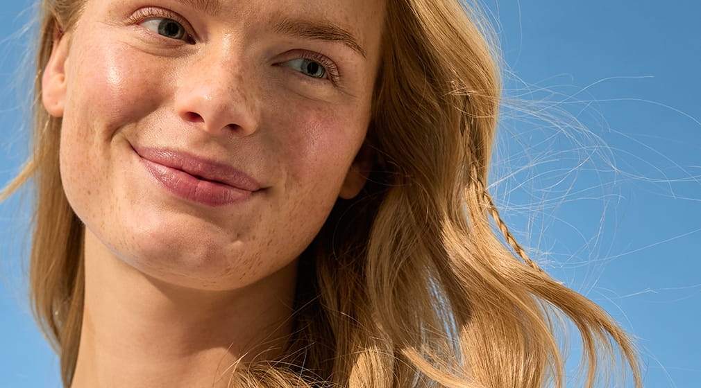 Jeune femme aux cheveux blonds debout au soleil
