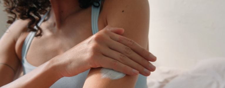mujer echándose crema en el brazo