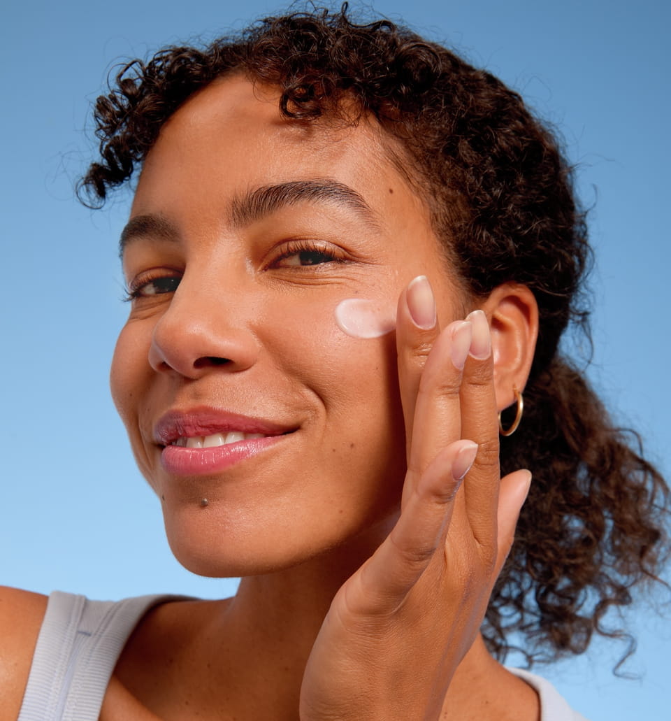 Jonge vrouw die gezichtscrème aanbrengt