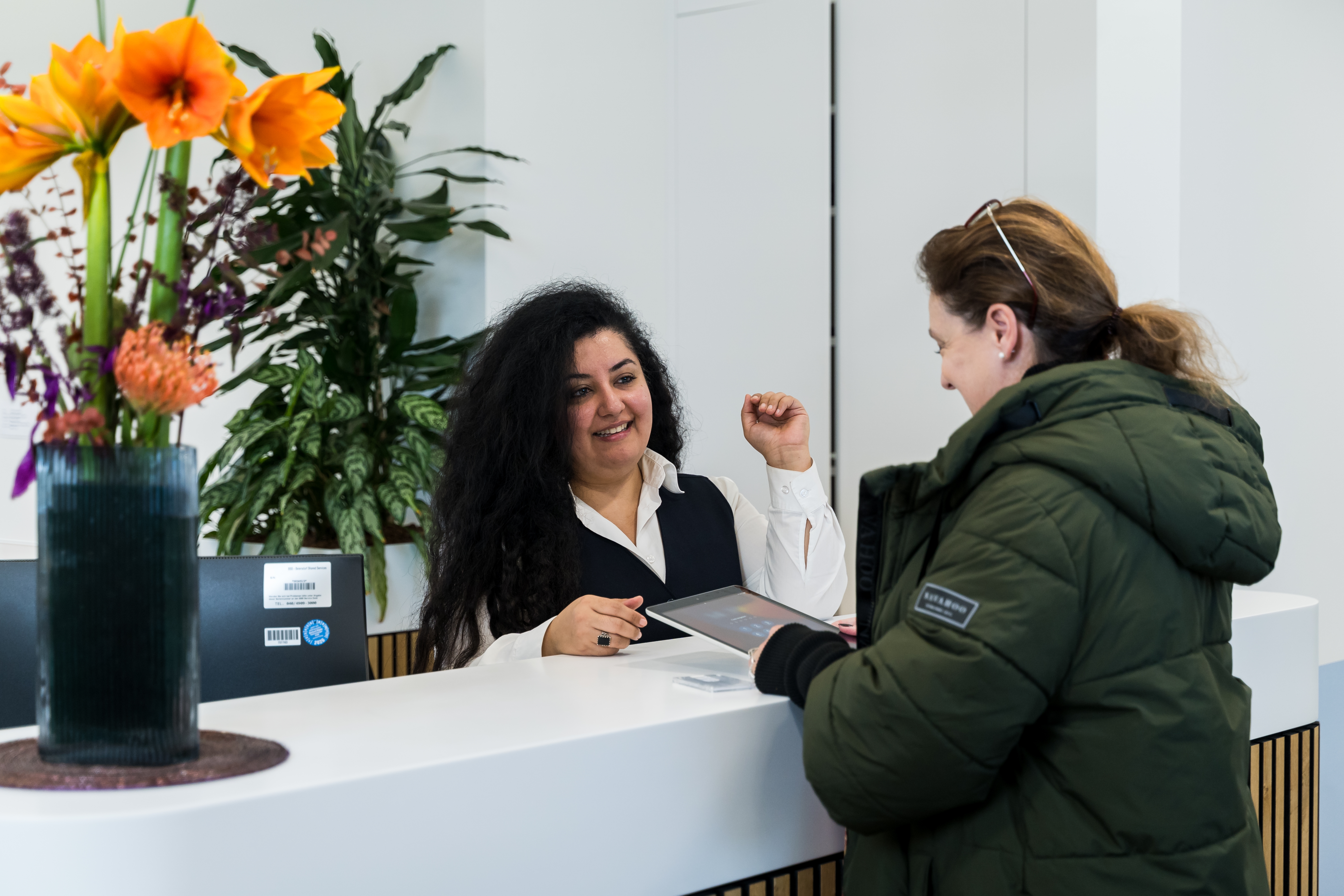 Three women sitting together, smiling and laughing outdoors.