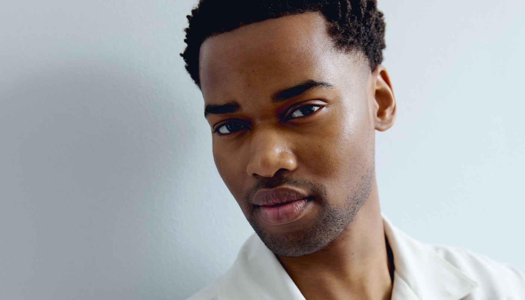 View of a person peering into the camera, against a grey background.
