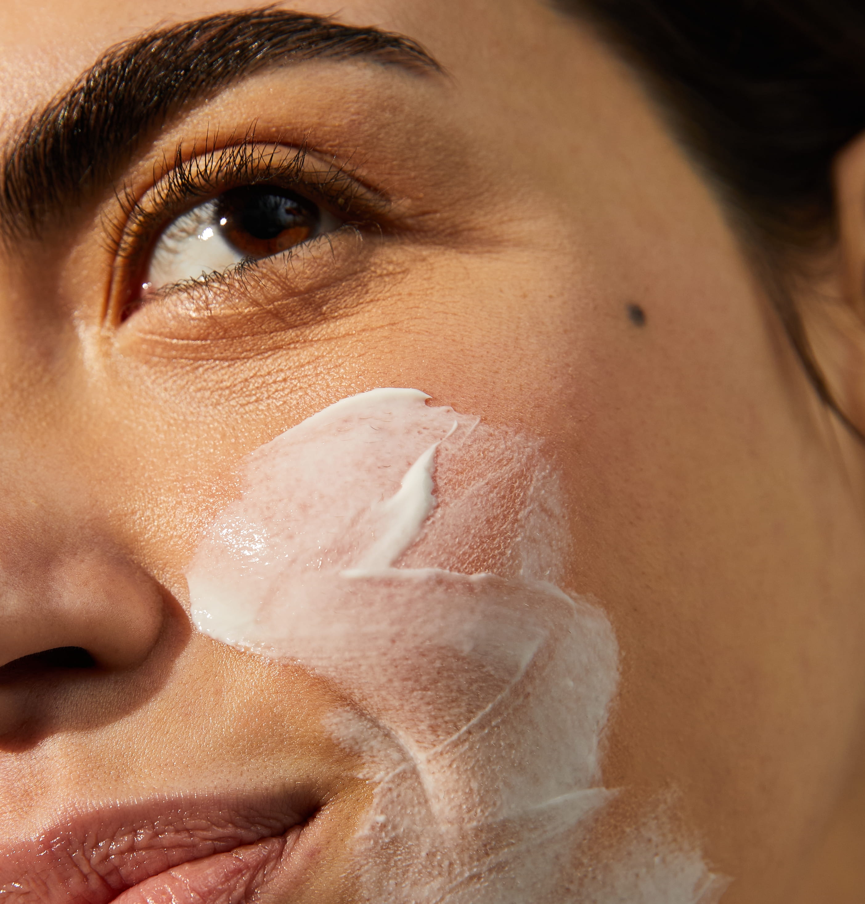 Inzoomat på kvinnas ansikte, hon har kräm på kinden och hakan