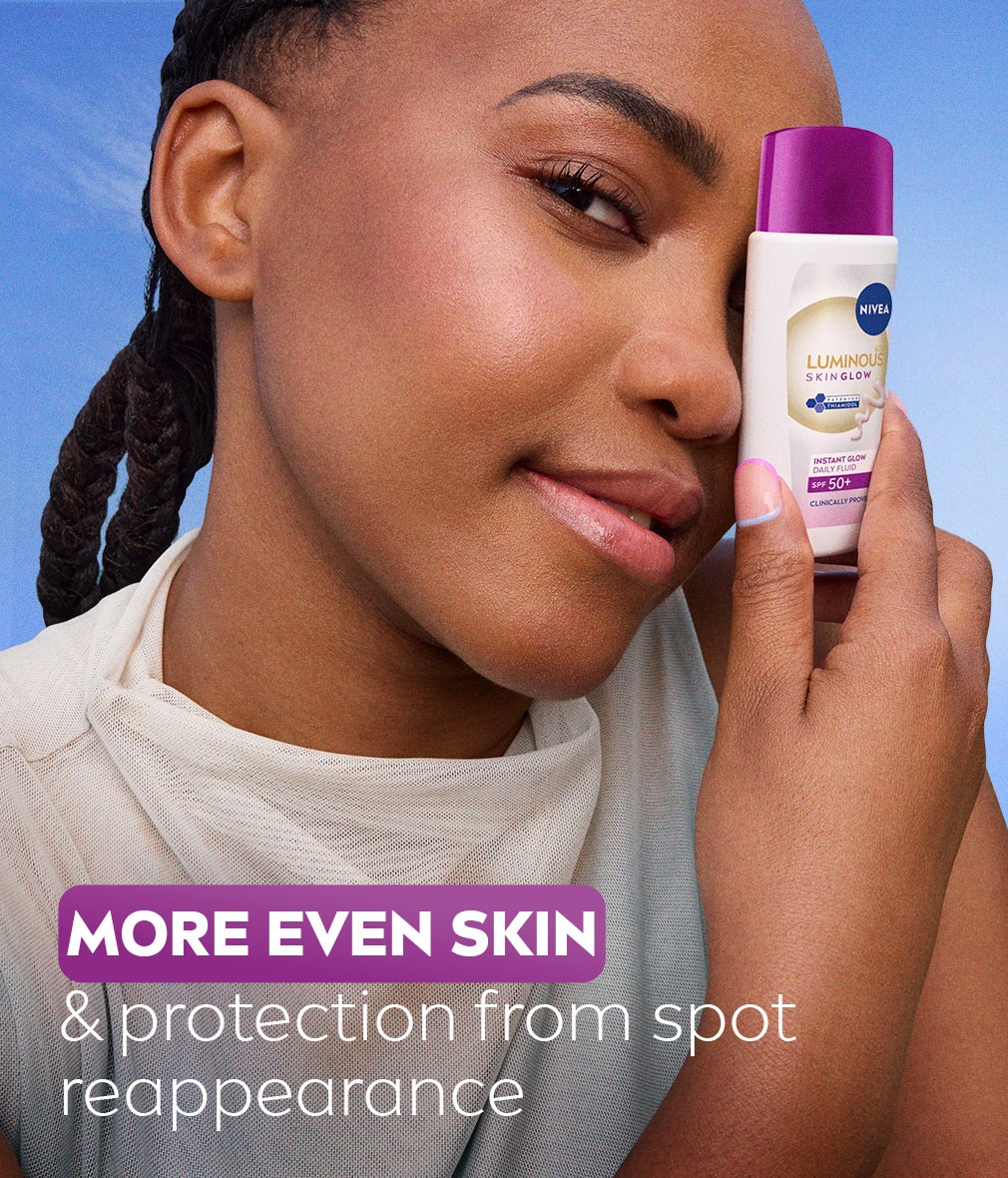 Young woman posing, holding NIVEA LUMINOUS630® SKIN GLOW Instant Glow Daily Fluid SPF 50+ to her face.