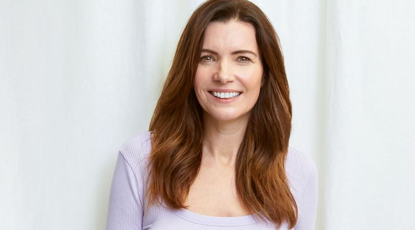 Eine Frau trägt am Strand einen kleinen Jungen auf dem Arm.