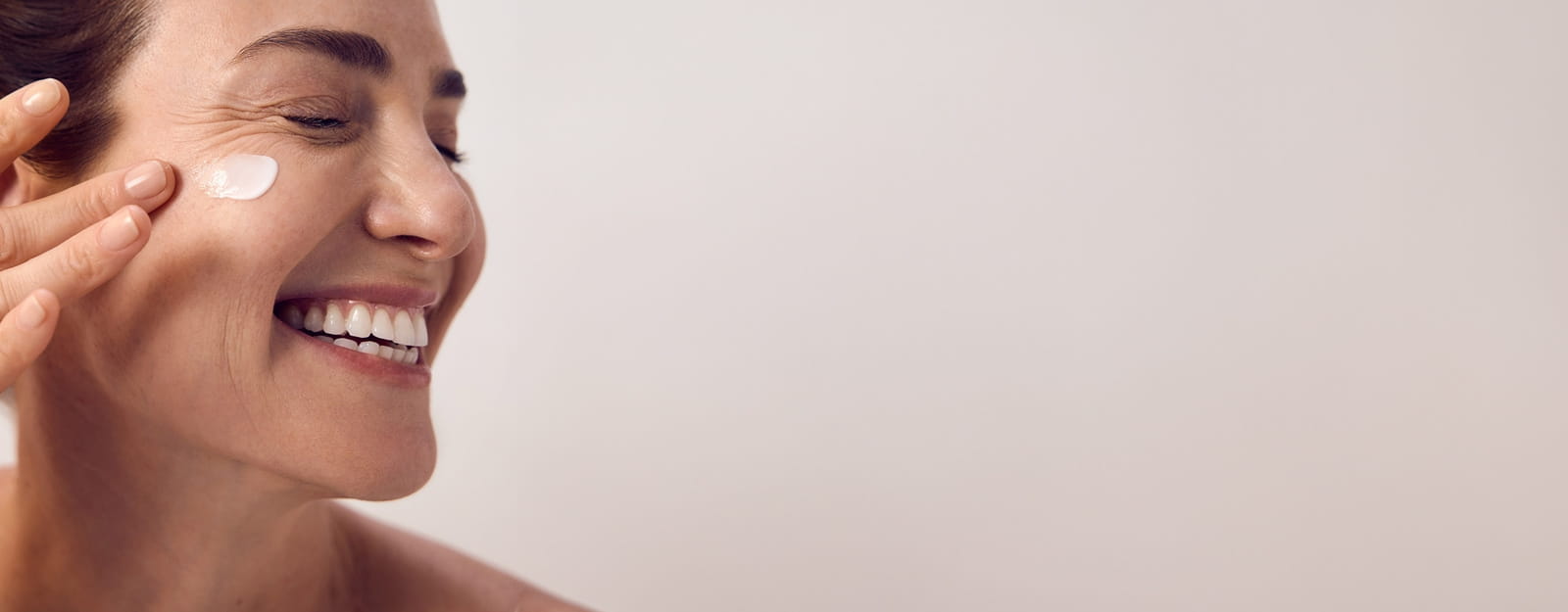 Une personne sourit avec un produit Nivea étalé sur le côté droit de son visage.