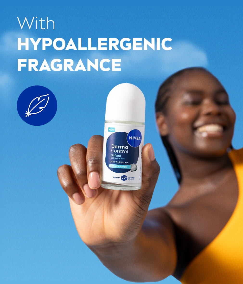 A blurred young woman smiles, with her hand in focus holding up the NIVEA Derma Control Restore Deo Roll-On.