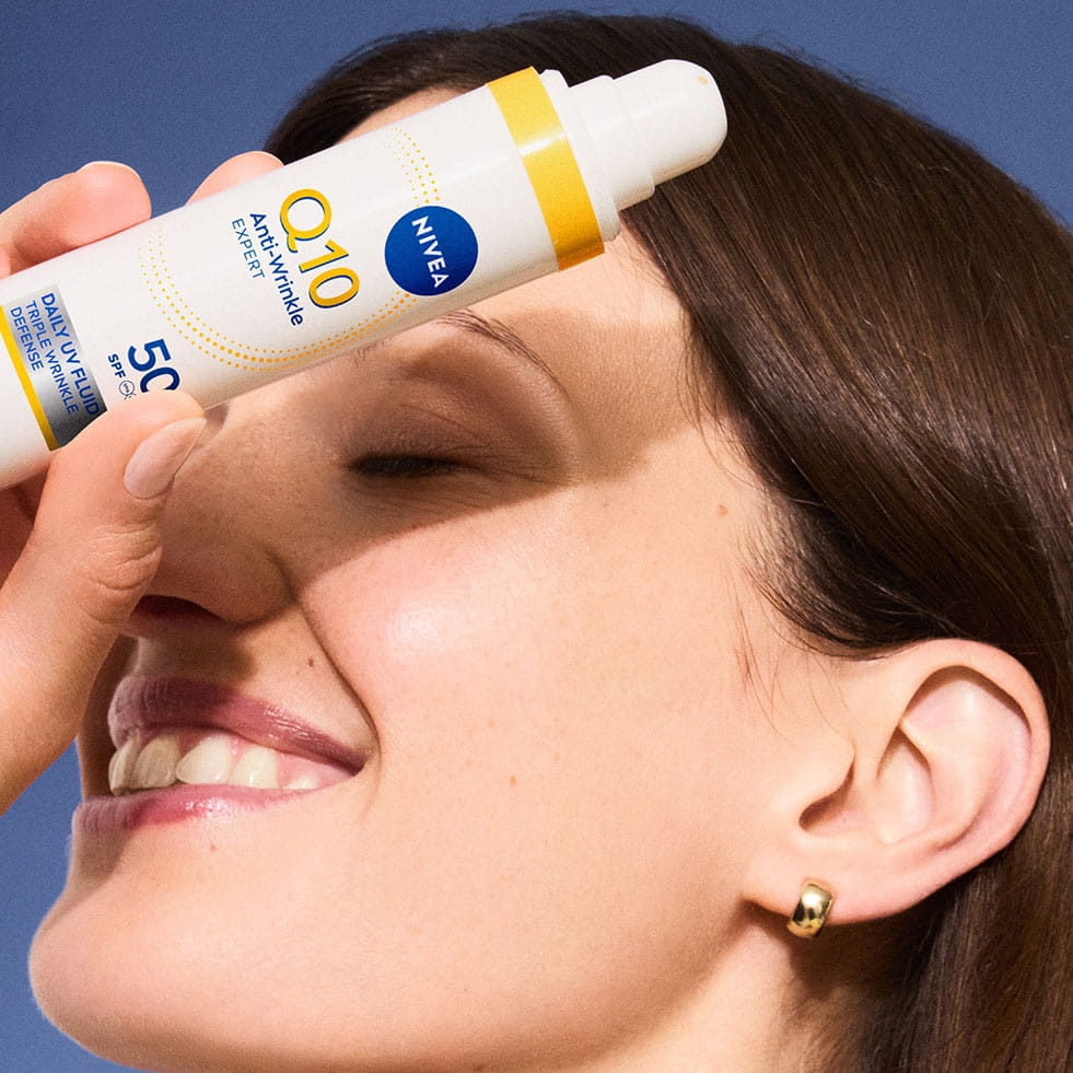 Q10 Triple wrinkle defense UV fluid uygulayan kadın, foto yaşlanmayı önlemede güneş korumasının önemini vurguluyor.
