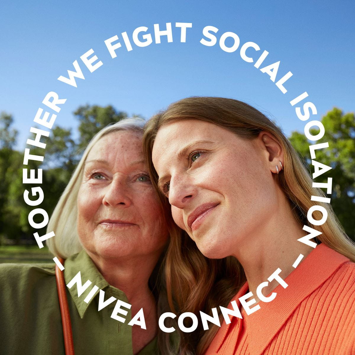 Two women looking off-camera with a blue sky and trees in the background.