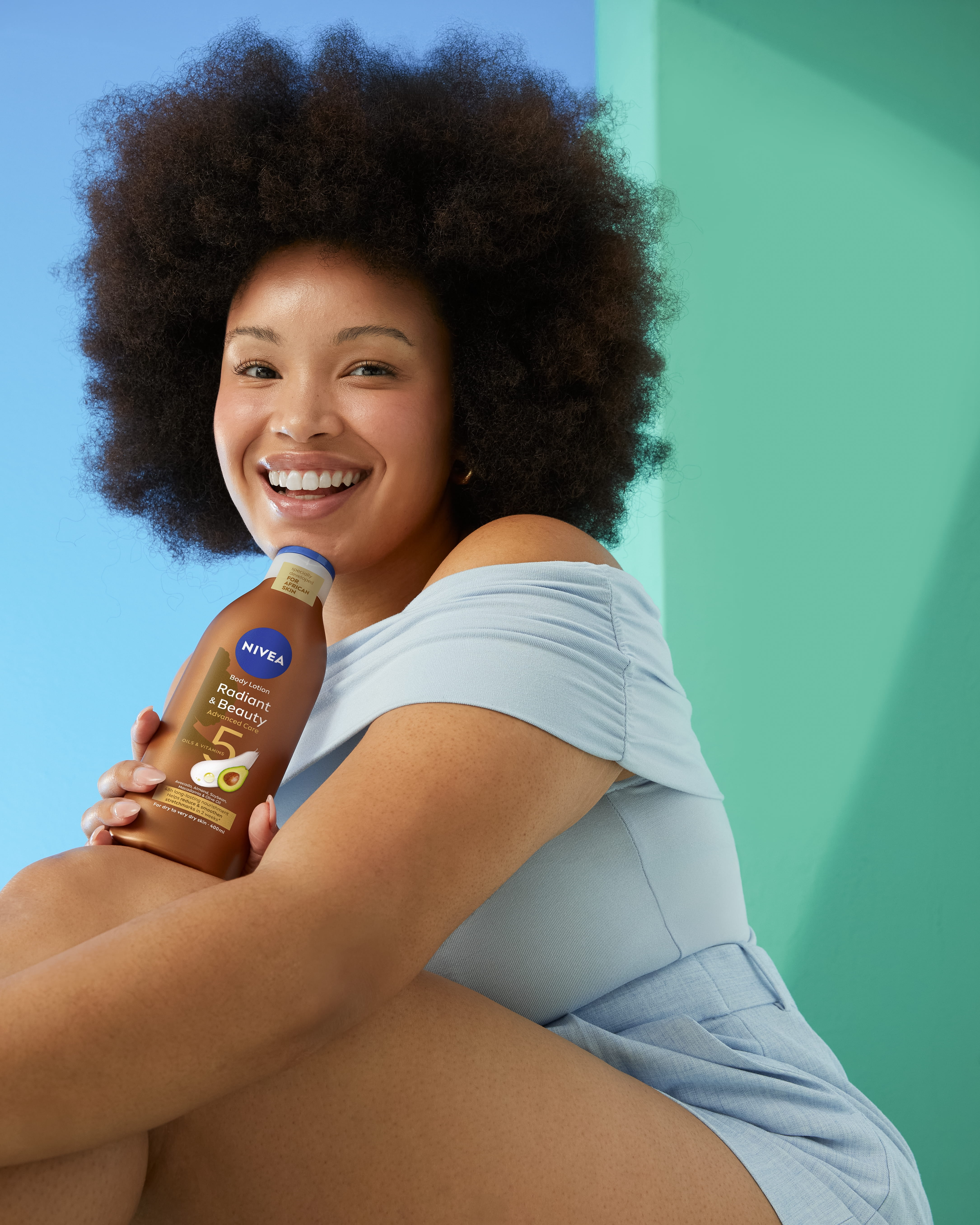 Joven con cabello afro utilizando la loción corporal Nivea Radiant and Beauty.