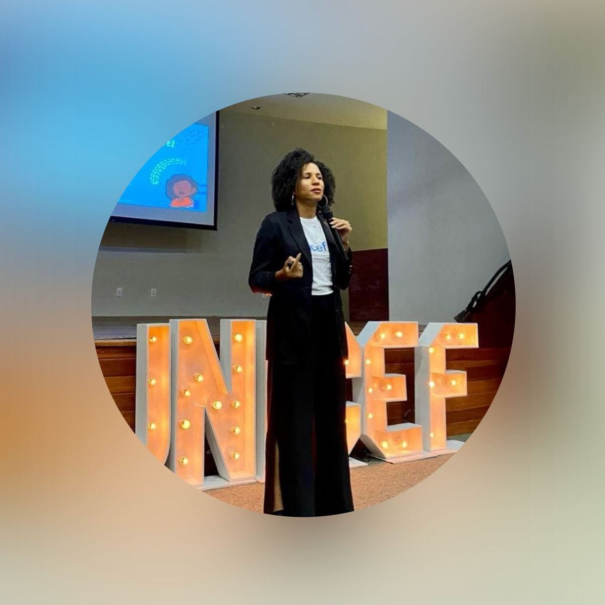 Woman giving a talk in front of a ‘UNICEF’ sign, with a presentation displayed behind her.