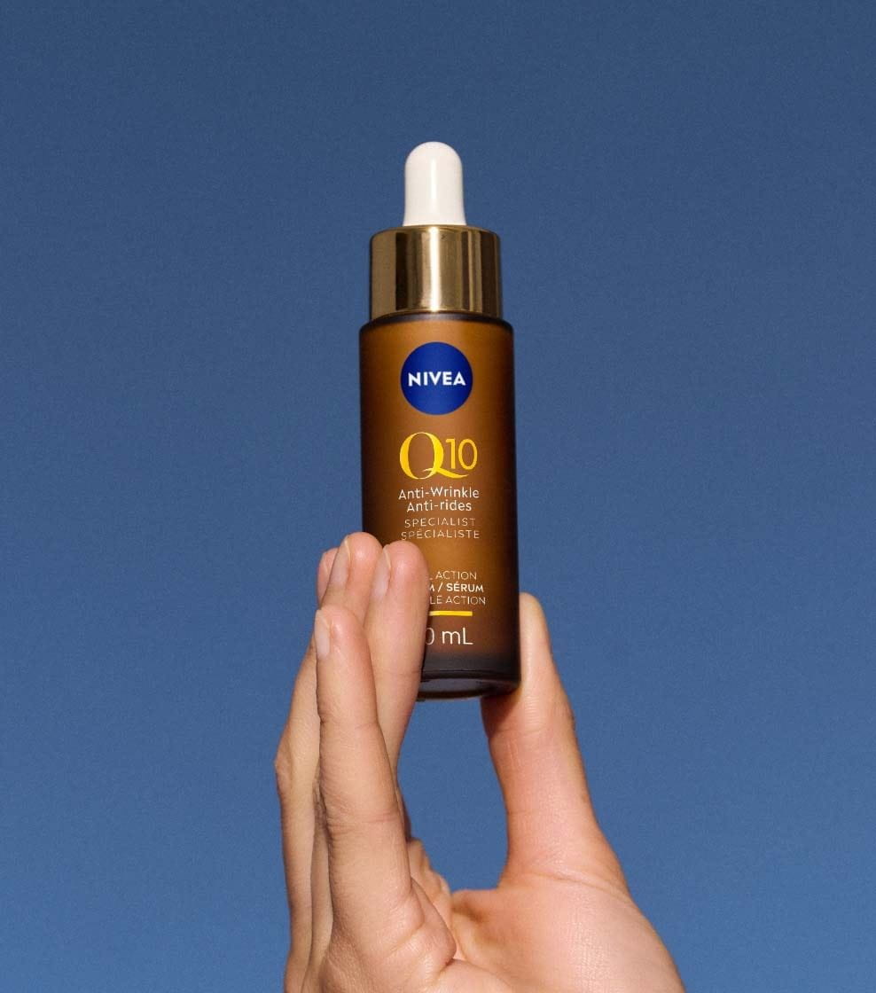 "A 30ml copper-brown bottle of NIVEA Q10 ANTI-WRINKLE SPECIALIST DUAL ACTION SERUM against a blue background. "