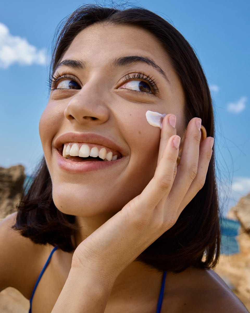 Strahlende Frau mit Sonnencreme im Gesicht