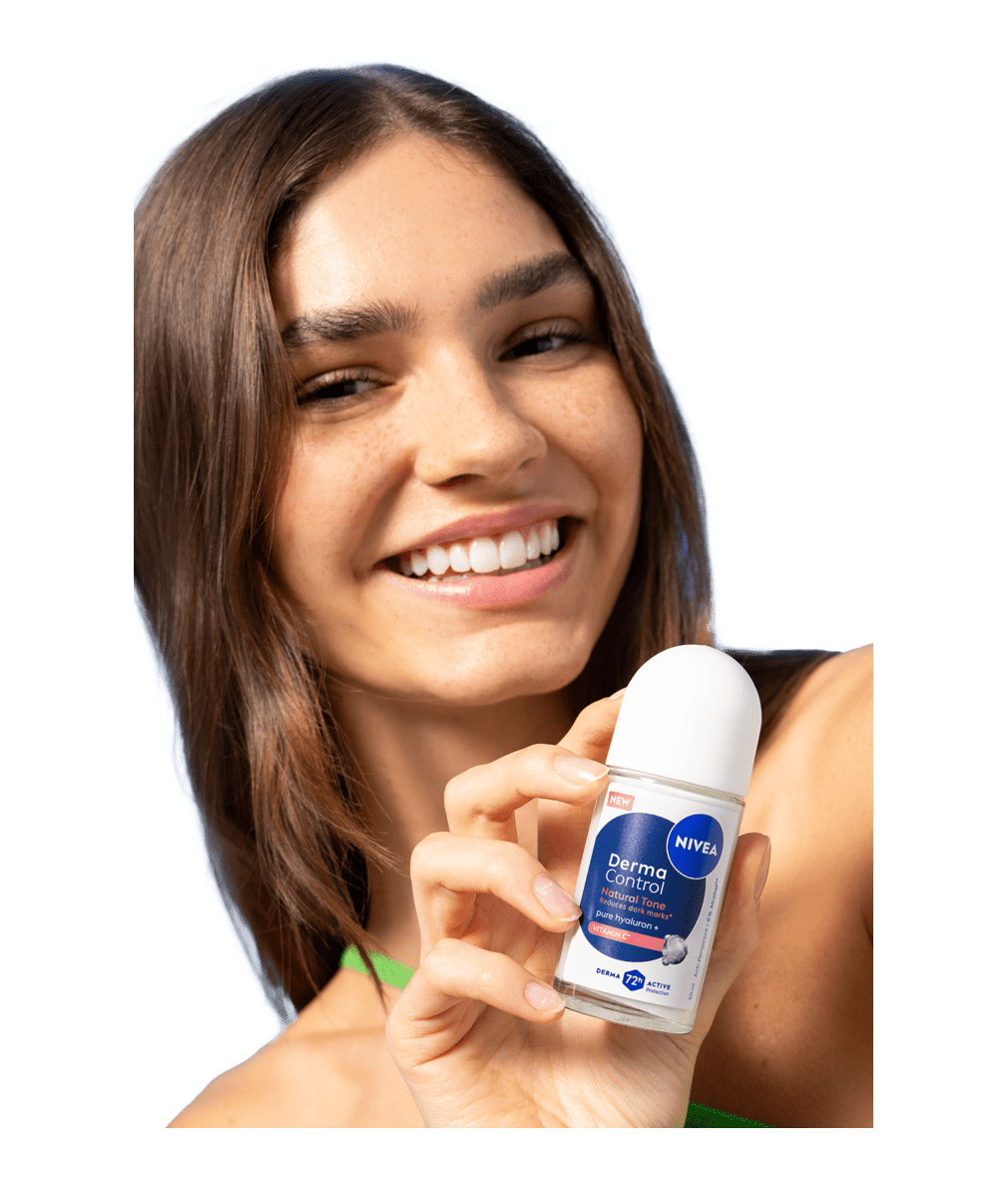 A young smiling woman turns her head while holding up NIVEA Derma Control Natural Tone Deo Roll-On.