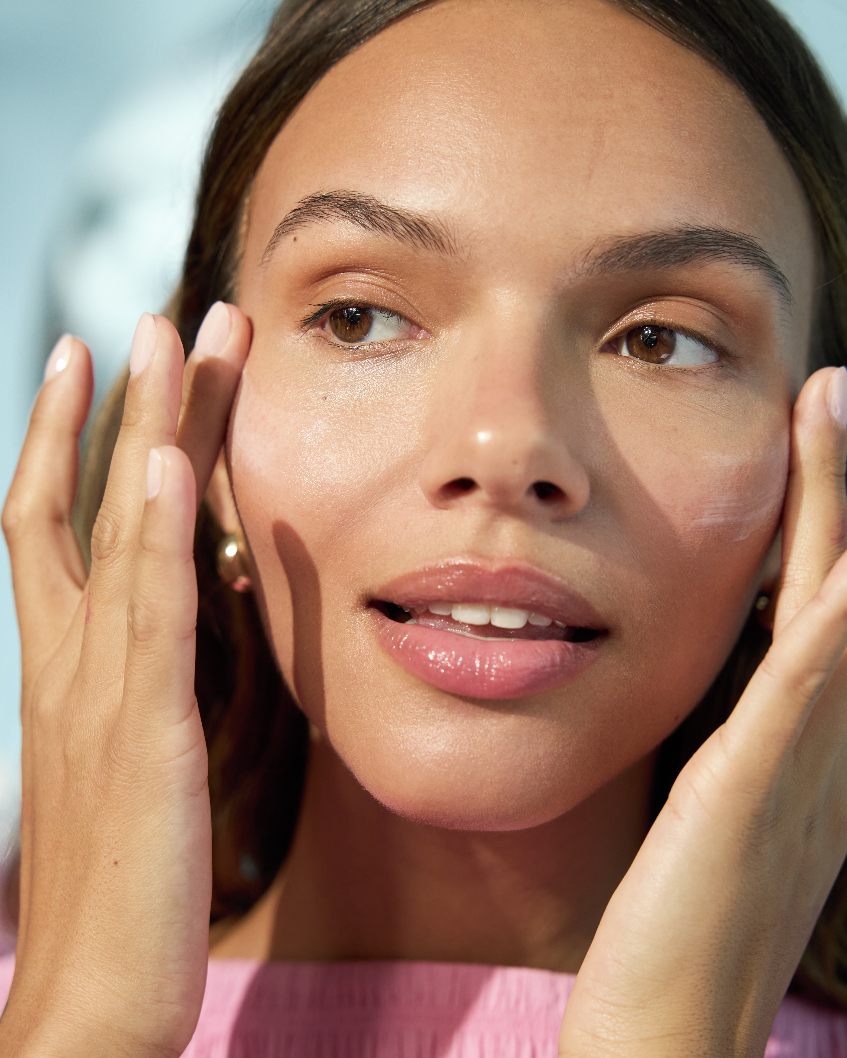 En person som applicerar kräm med fingrarna på kinderna