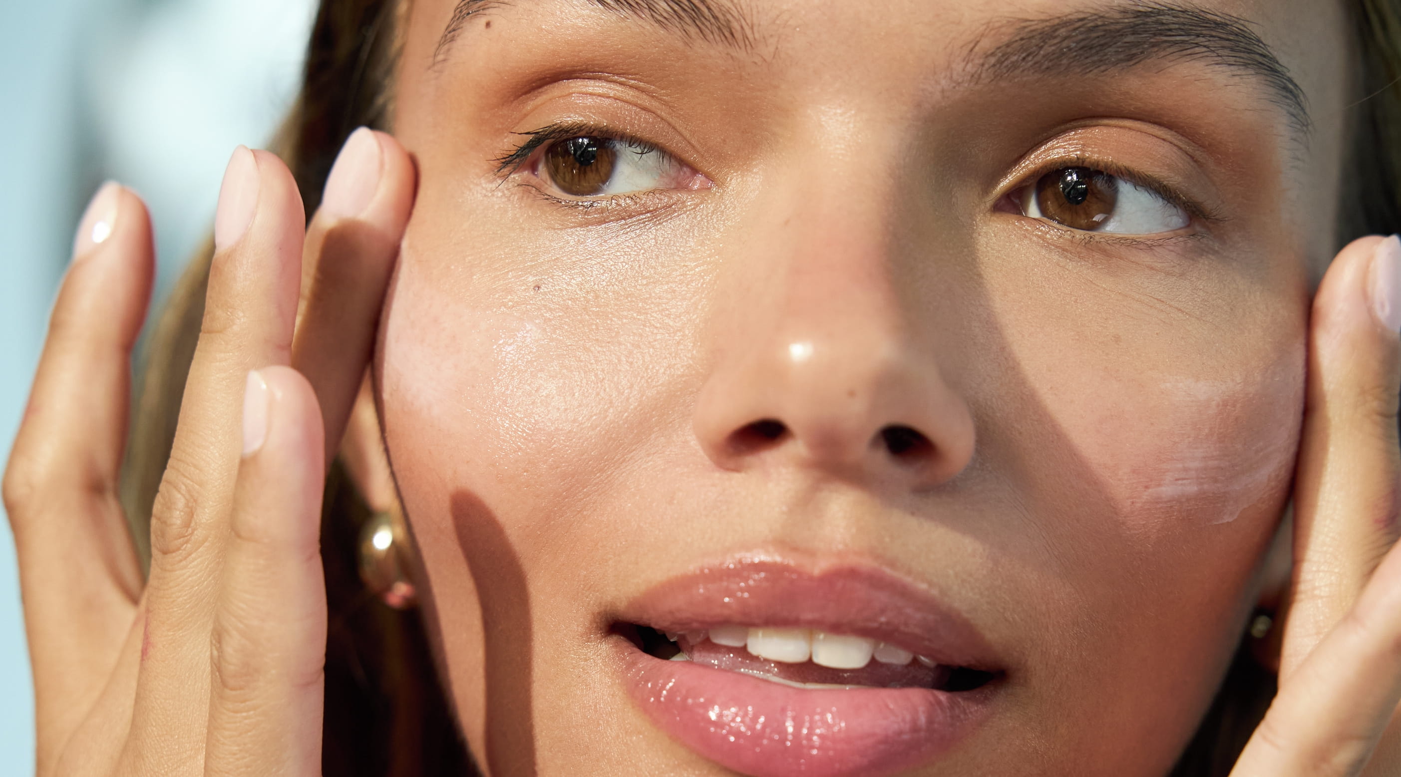 En person som applicerar kräm med fingrarna på kinderna