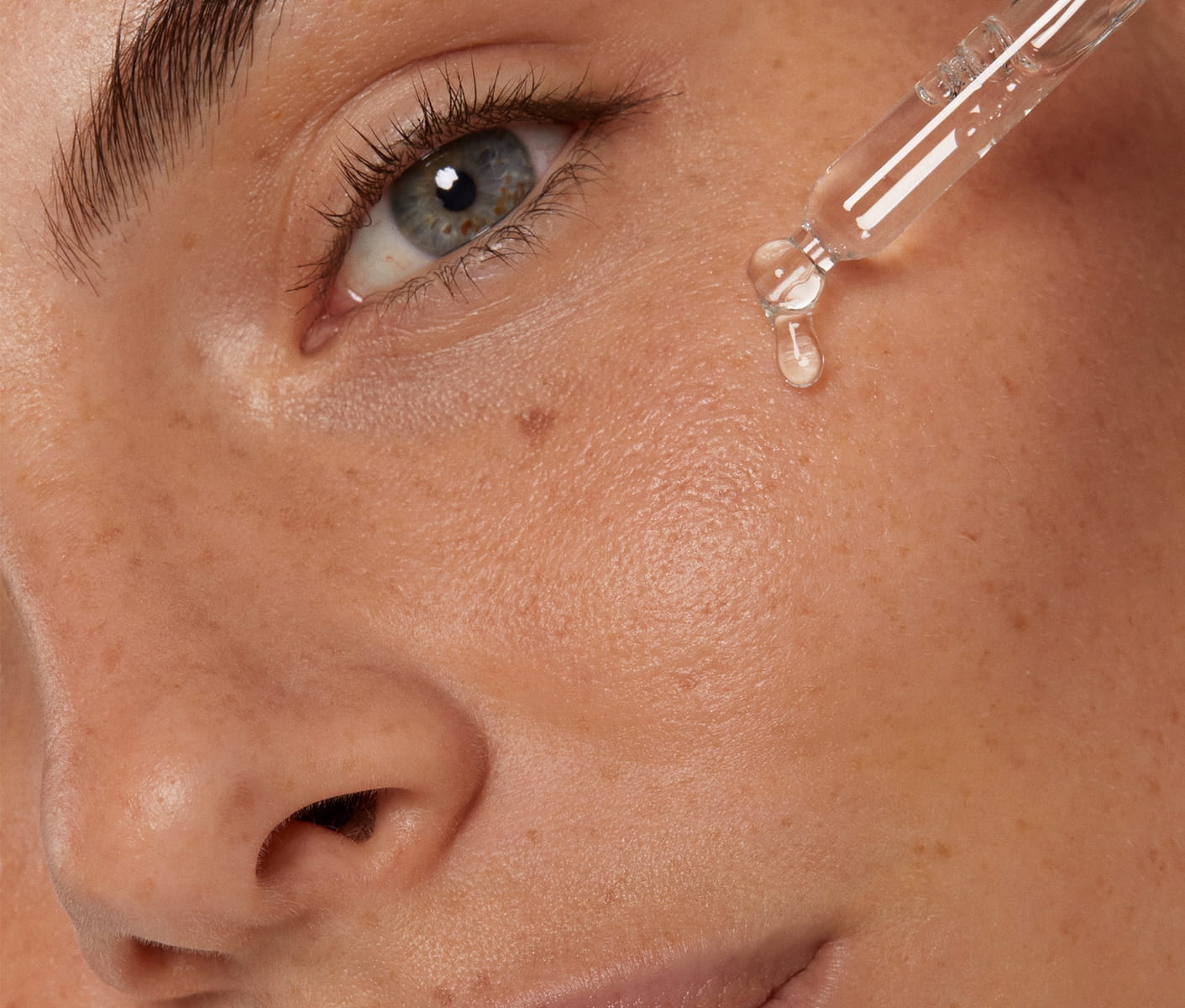 Close up of a woman's face with healthy skin applying NIVEA's New Cellular Serum with a lightweight texture