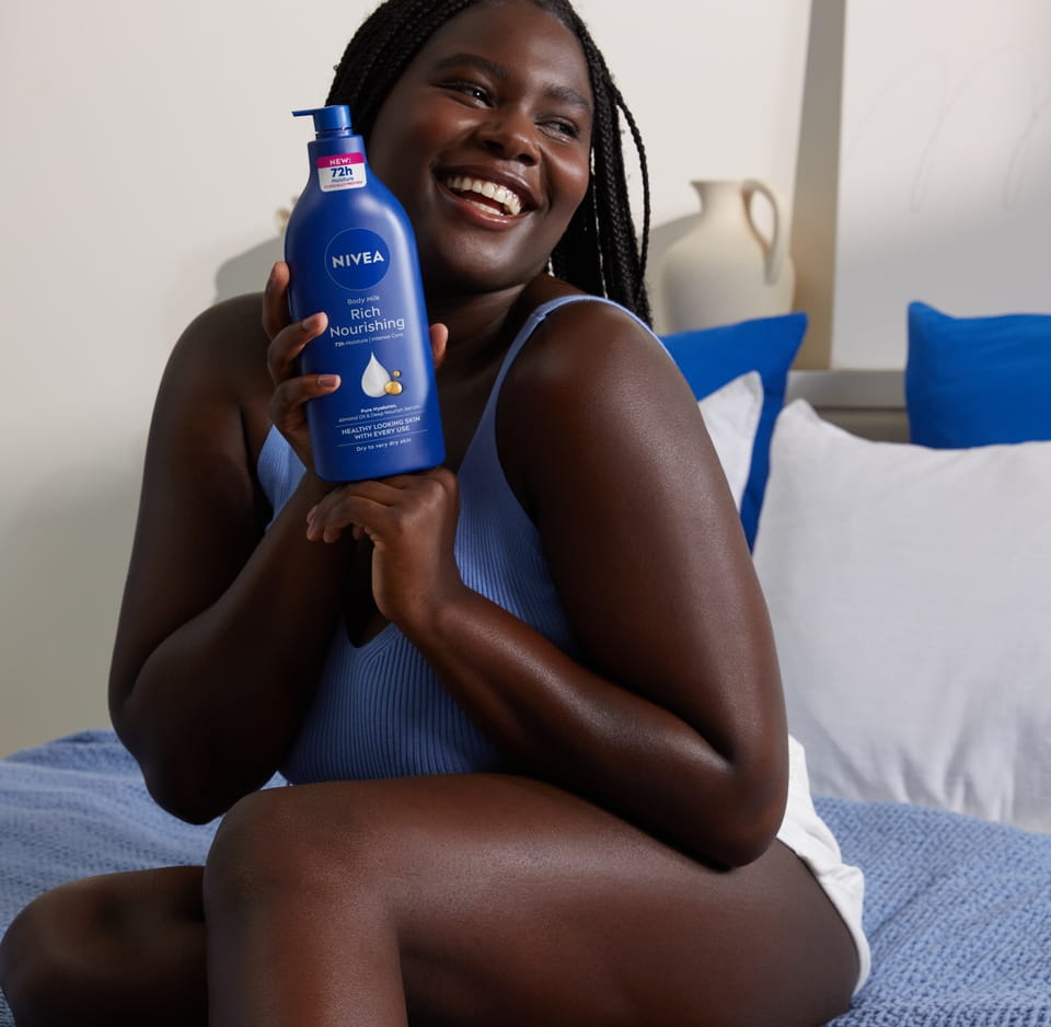 Young black woman using Nivea Body Milk Rich Nourishing with Almond Oil
