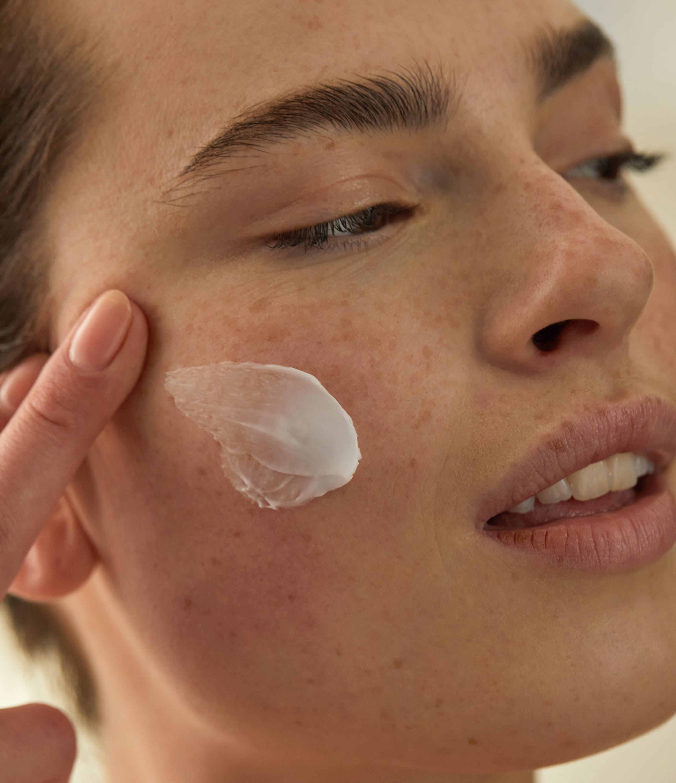 kvinna applicerar ansiktskräm i ansiktet