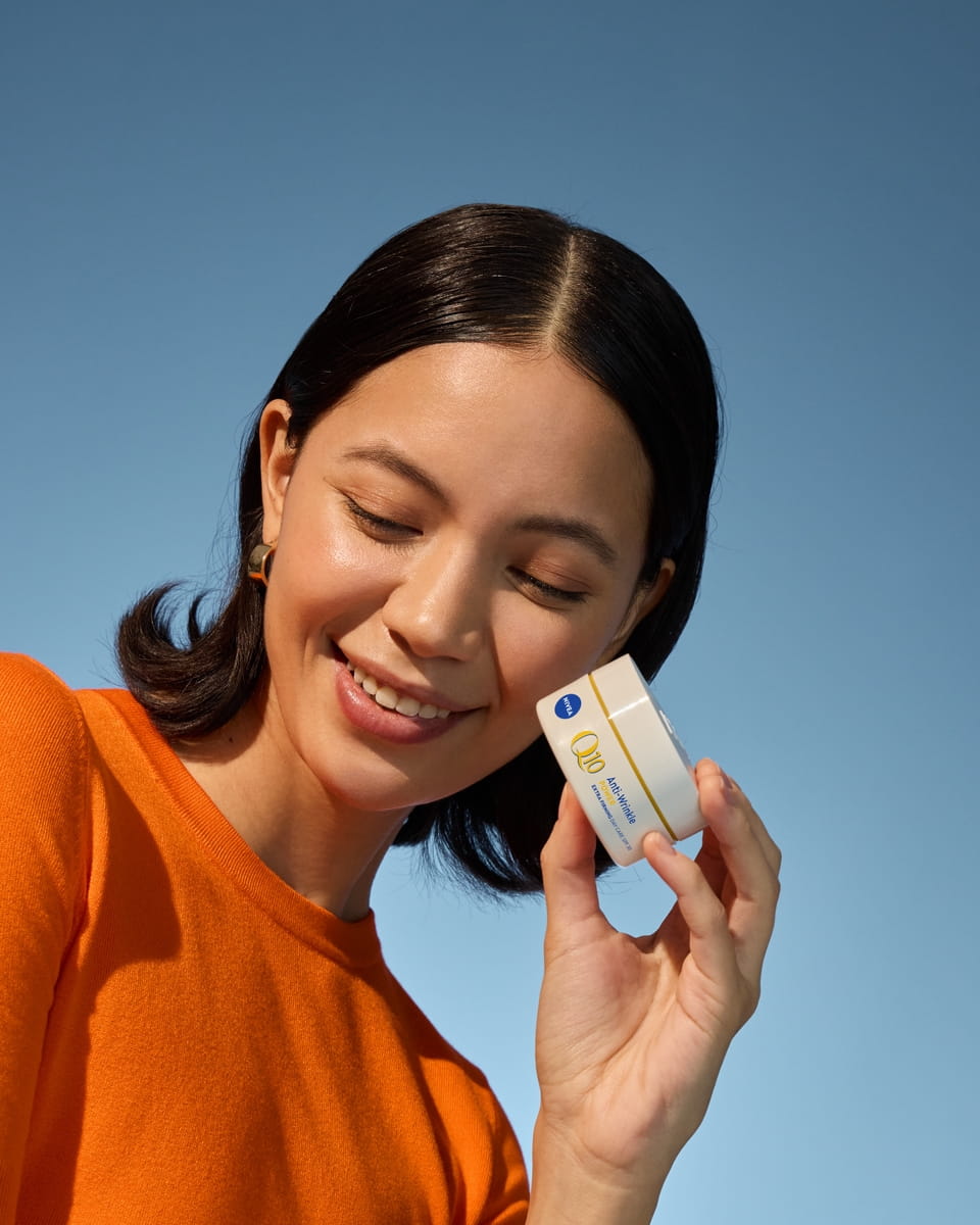Młoda kobieta stosująca krem do twarzy Nivea Q10 Anti-Wrinkle Power