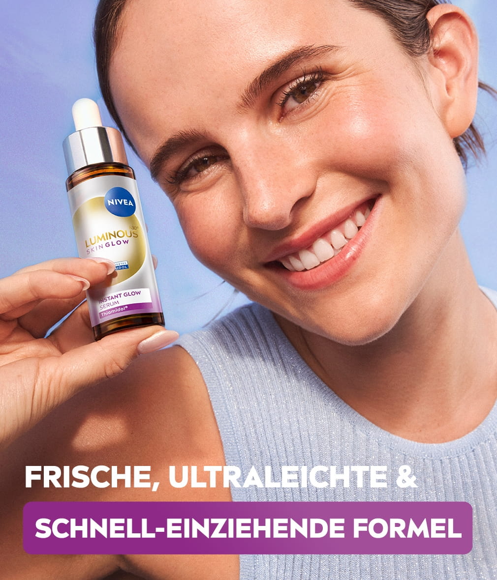 Eine junge Frau lächelt fröhlich und zeigt ein Fläschchen NIVEA LUMINOUS630® Skin Glow Instant Glow Serum vor himmelblauem Hintergrund.