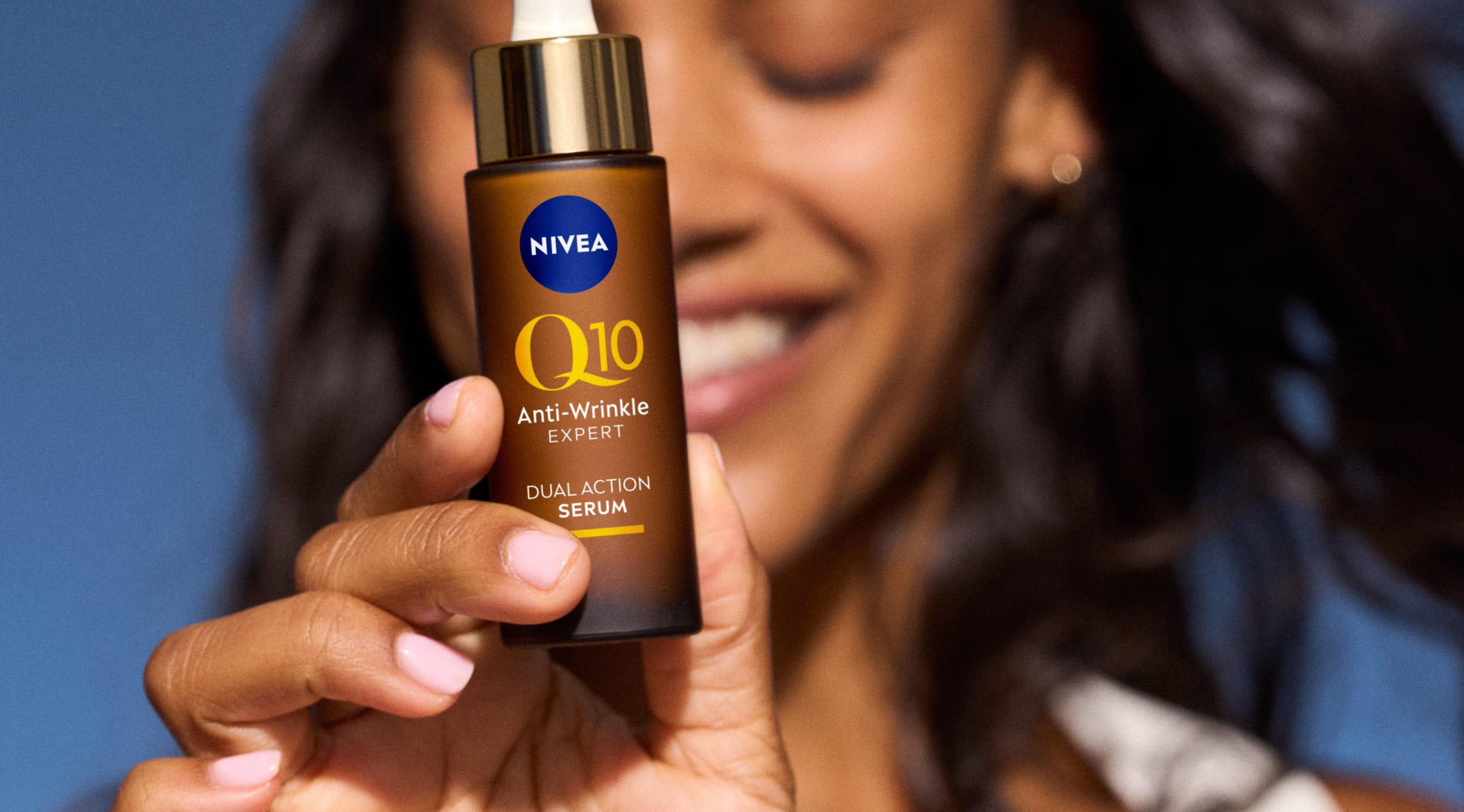 ung kvinna leende som håller upp NIVEA Q10 serum