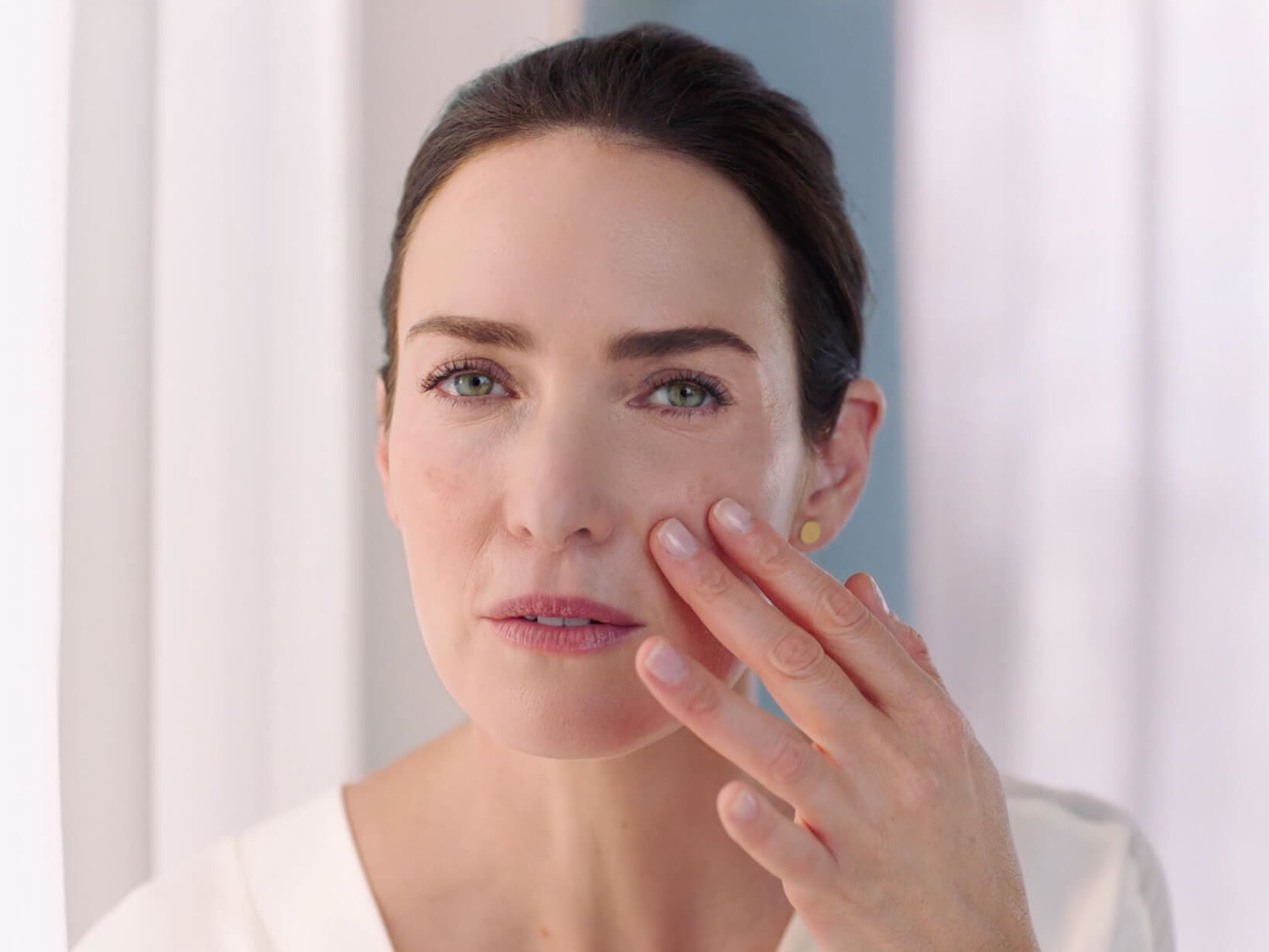 Woman applying dark spot cream onto her face