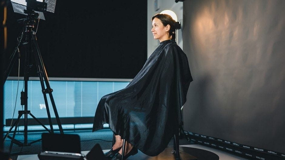 Person seated in a studio with lighting equipment.