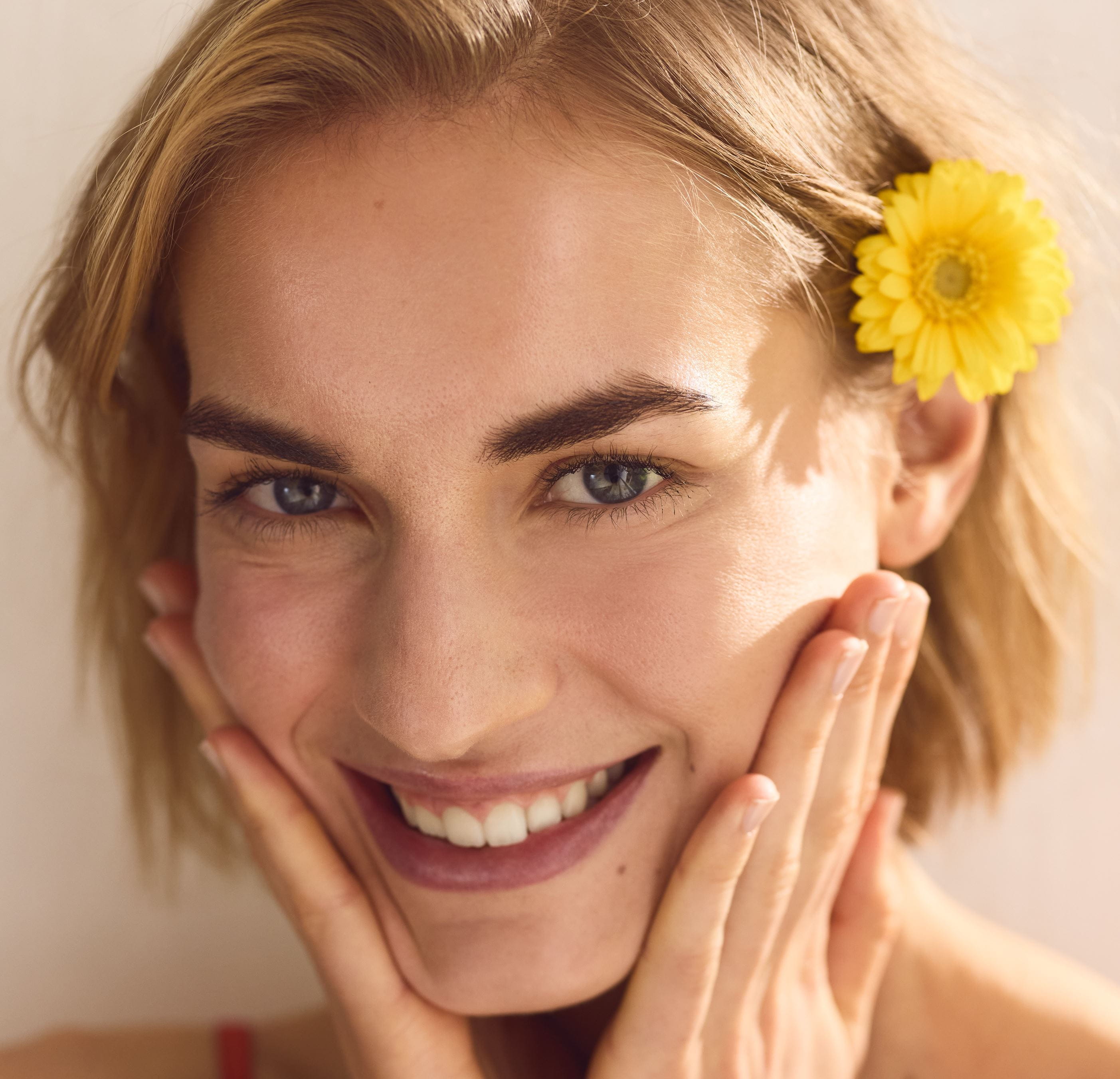 Usmievajúca sa žena s kvetom vo vlasoch