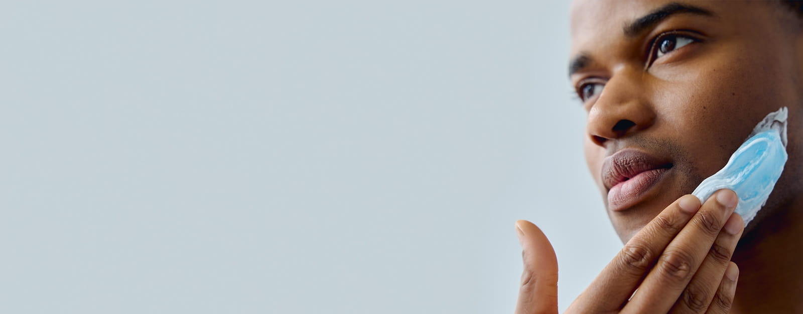 A person seen staring off into the distance with a Nivea product smeared onto the left side of their face.