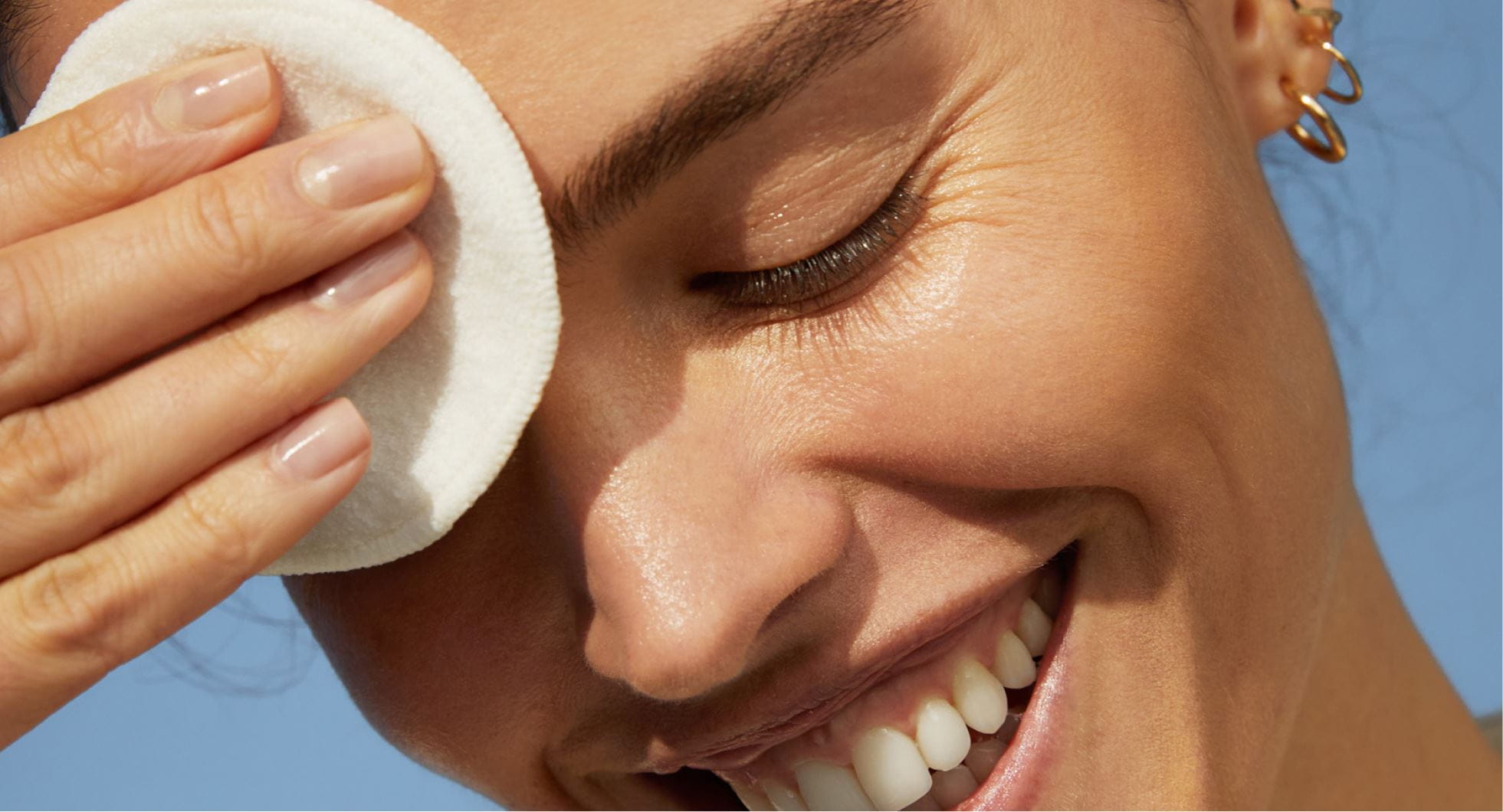 A woman with healthy skin cleansing her face with a cototn puff
